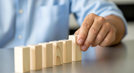 Hand placing wooden block in a row of blocks on a table male person