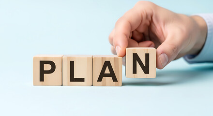 Hand placing wooden block spelling out P L A N on light blue background plan planning