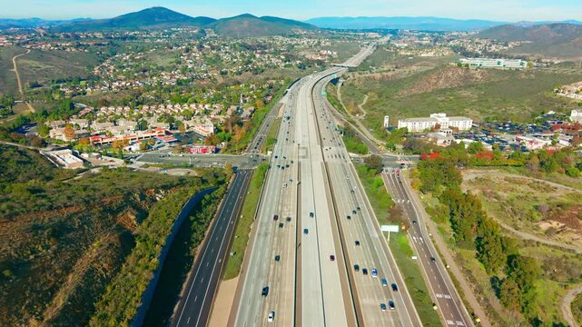 Aerial view of Mira Mesa road in San Diego showing freeway traffic, residential areas, and surrounding hills under clear California skies.