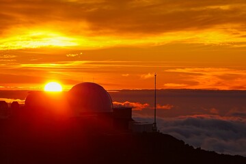 The sun sets above the clouds at the summit of the Haleakala volcano on Maui