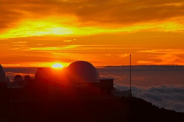 The sun sets above the clouds at the summit of the Haleakala volcano on Maui