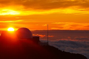 The sun sets above the clouds at the summit of the Haleakala volcano on Maui