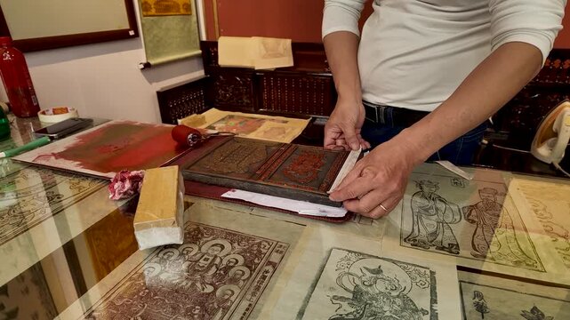 A traditional artisan carefully prints folk artwork on d&oacute; paper, preserving a centuries-old Vietnamese craft through skilled hands and quiet dedication. 