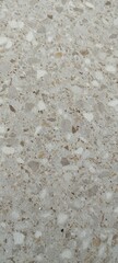 A texture shot of a beige and grey speckled terrazzo stone floor tile