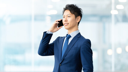 スマートフォンで通話をする笑顔の男性ビジネスマン