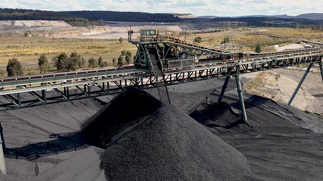 Drone footage of mining machinery dumping coal on storage pit in Ulan near the Australian outback