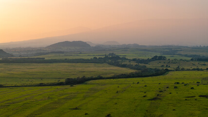Aerial view of green fields and distant mountains over Maui, Hawaii landscapes during morning...