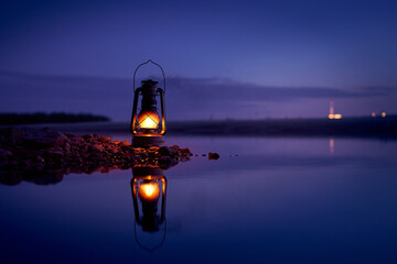 Burning old lantern on rocks reflecting in the river © Mikhail Mishchenko