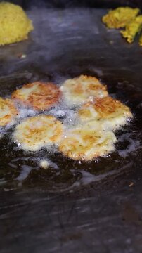 Tikki an indian street food being fried in oil on a pan