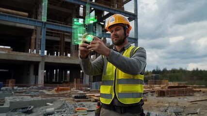 Construction Worker Uses Smartphone for Measuring and Surveying at Building Site in Daylight