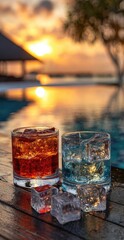 Two colorful cocktails with ice cubes on a wooden surface at sunset by a pool.