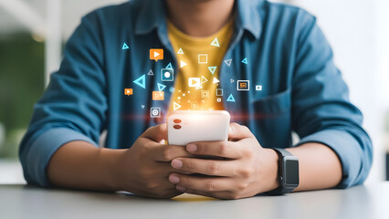 A person holding a smartphone with floating digital icons above it on a table indoors