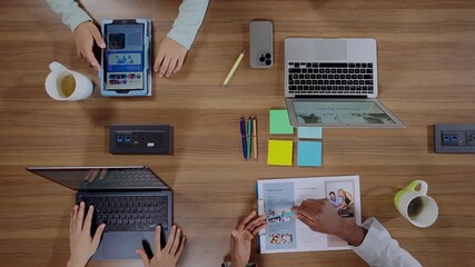 Top View of Creative Business Team Collaborating at Wooden Office Desk with Laptops and Tablets