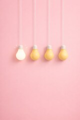 Standout Bright Light Bulb Among Yellow Bulbs on Pink Background &mdash; Innovation and Creativity Concept