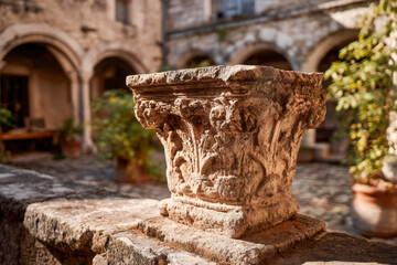 Limewashed stone pedestal with chipped edges in sunlit courtyard and soft arches background