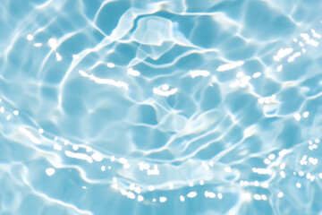 Blue water with ripples on the surface. Defocus blurred transparent blue colored clear calm water surface texture with splashes and bubbles. Water waves with shining pattern texture background.