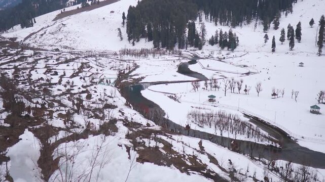River Lidder flowing amidst the snowy landscape of the mountain valley during the winter season at Betaab Valley near Pahalgam in Jammu and Kashmir, India. Scenic view of river in winter at Kashmir. 