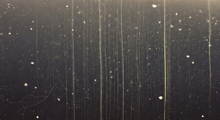 Close-up view of a dark surface with streaks and specks illuminated by a light source from above with a moody atmosphere.