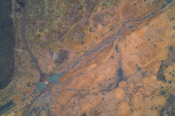 Dry military landscape with dirt road and small river, rough tactical terrain texture and autumn field, aerial top view drone shot