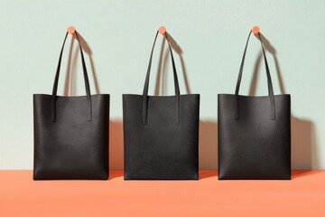 Three Black Leather Tote Bags on Orange Surface light green wall