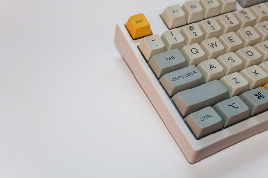 White mechanical keyboard with bright yellow Esc key on white background, minimalism, keyboard buttons. A keyboard with a yellow key and red volume button. High quality