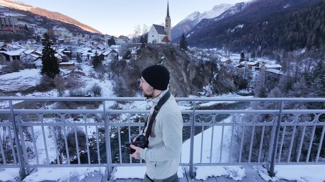 Man Walking Across Icy Bridge in Swiss Alpine Village During Winter &ndash; Snowy Mountains, Rural Switzerland and Cold Seasonal Atmosphere
