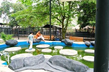 Father and son spending time at an eco friendly outdoor playground designed with natural elements. Represents sustainable recreation, healthy childhood, and positive family relationships.