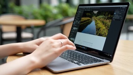 Hands typing on laptop displaying scenic landscape thumbnails outdoors - Powered by Adobe