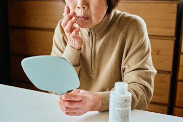 顔に保湿クリームを塗るシニア女性