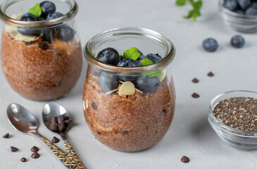 Chocolate chia pudding with blueberry and almonds in glass jars on gray background. Healthy food