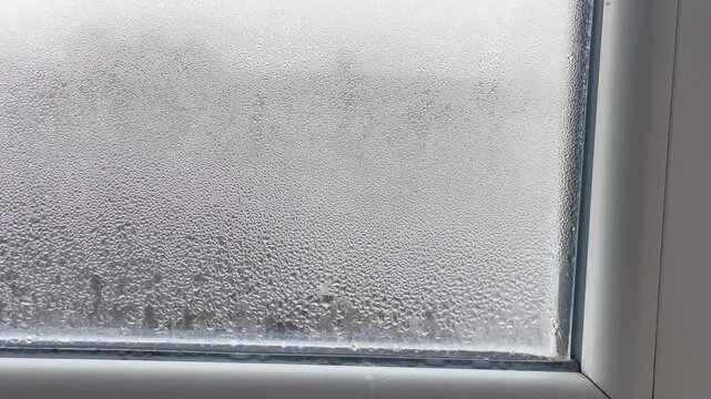 Condensation, mold, high humidity in the house. Foggy windows, humidity problem. high humidity in the house. hand wipes off water condensation from plastic window glass in the room