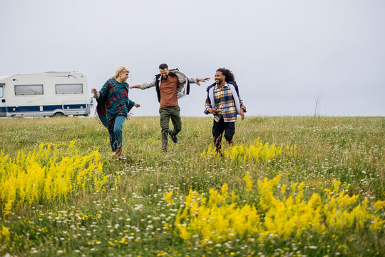 Friends running freely in nature with motorhome camping