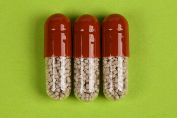 Three Pharmaceutical Capsules on Green Background Healthcare Concept
