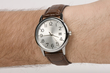 Classic silver analog wristwatch with brown leather strap on male wrist