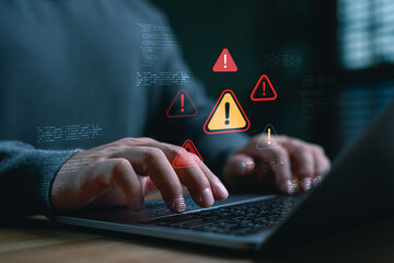 Cybersecurity warning concept with alert icons and coding on laptop screen. Businessman facing system error, malware threat, hacking risk, or data breach during software development or online work.