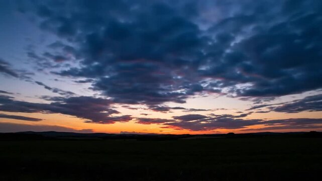 Time-lapse of vibrant sunset over green field with fluffy clouds and blue sky during golden hour