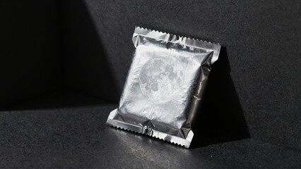 Silver foil packet with moon design on dark surface