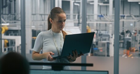 Woman Monitoring Automated Systems on Laptop. Technical Specialist Using Laptop Check or Diagnose Automated Industrial Systems. Real Time System Monitoring, on Site Diagnostics, Process Optimization.
