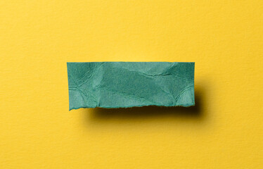 One single green torn ripped wrinkled crumpled blank paper note with shadow and copy space for text on yellow background