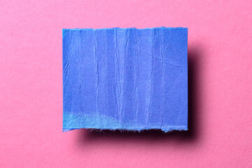 One single blue torn ripped wrinkled crumpled blank paper note with shadow and copy space for text on pink background