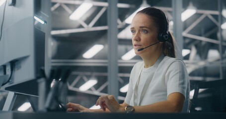 Specialist Manages Network Systems From Workstation in Network Operations Center. Woman Wearing Professional Headset Coordinate Tasks. Proactive System Monitoring and Coordinated Digital Operations.
