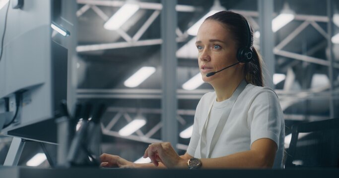 Specialist Manages Network Systems From Workstation in Network Operations Center. Woman Wearing Professional Headset Coordinate Tasks. Proactive System Monitoring and Coordinated Digital Operations.