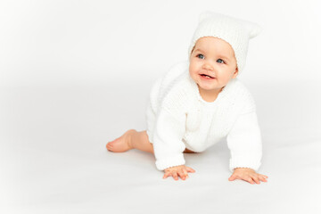 a baby crawls on a white isolated background, a place for text, a baby in a knitted white suit and...