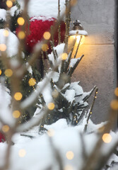 The Christmas tree, decorated with garlands, stands outside; it was snowing.