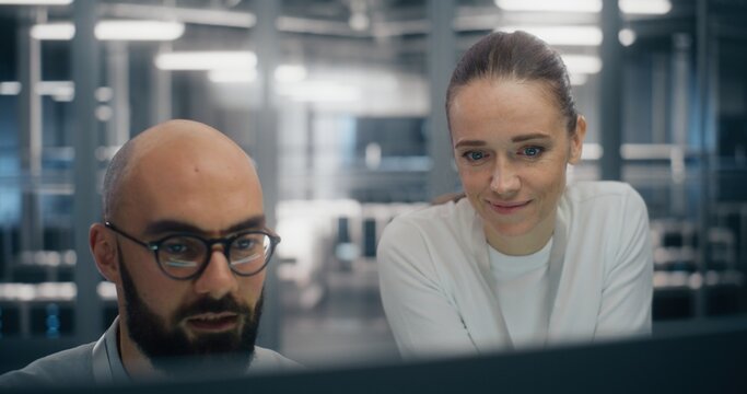 Team Consulting Over Console in Control Room. Digital infrastructure experts consulting over workstation console, deeply engaged in technical discussion. Concept of enterprise level system management.
