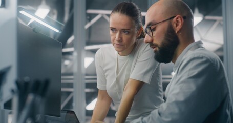 Engineers Reviewing Network Performance Data. Male and Female IT Engineer Team Collaborating Over Computer Monitor to Review Critical Network Performance Metrics. Teamwork and Real Time IT Monitoring.