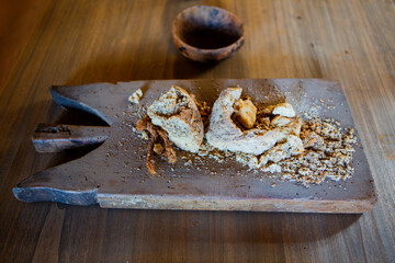 Rustic bread pieces rest on wooden board surrounded by crumbs creating warm vintage atmosphere with artisanal food charm.