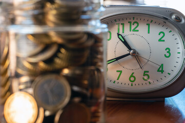 Coins In Glass Jar And Green Analog Clock Symbolizing Saving, Time, And Finance