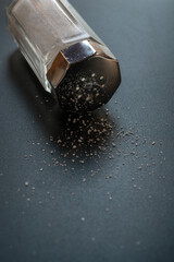Close-Up Salt Shaker Spilling Salt Crystals On Dark Table Surface