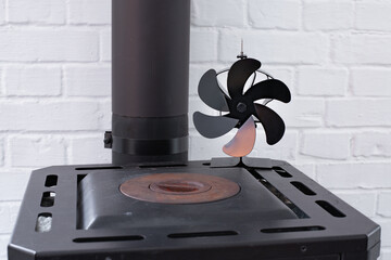 Stove fan heat powered. Black heat stove fan on the top of wood stove to improve heat circulation. Eco-friendly home heating concept